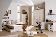 Modernes Jugendzimmer mit einem 140x200 cm Bett, Schreibtisch und Schrank in heller Holzoptik. Perspektive: seitliche Ansicht des Bettes mit Stauraum.