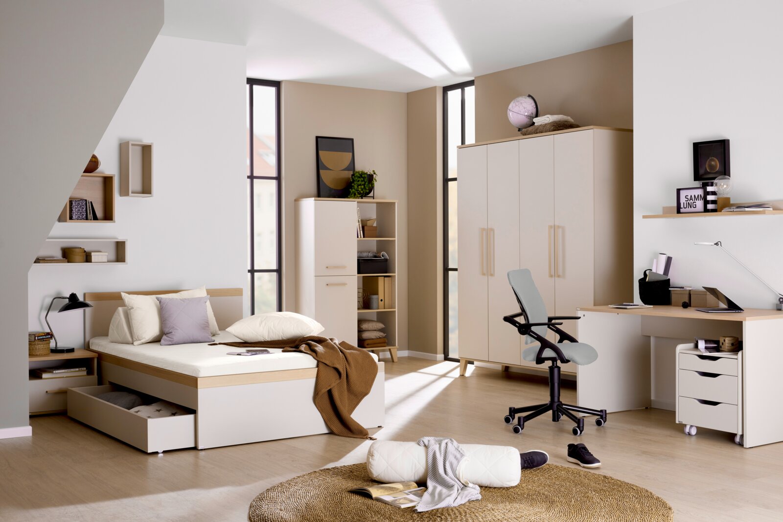 Modernes Jugendzimmer mit einem 140x200 cm Bett, Schreibtisch und Schrank in heller Holzoptik. Perspektive: seitliche Ansicht des Bettes mit Stauraum.