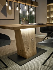 Moderner Esstisch aus Holz mit zentralem Sockel, umgeben von stilvollen Stühlen, aus der seitlichen Perspektive betrachtet.