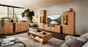 Wohnzimmer-Set aus massivem Holz mit Sideboard, TV-Lowboard, zwei Vitrinen mit warm beleuchteten Akzenten und Couchtisch, frontal in einer modernen Wohnraum-Szene fotografiert.