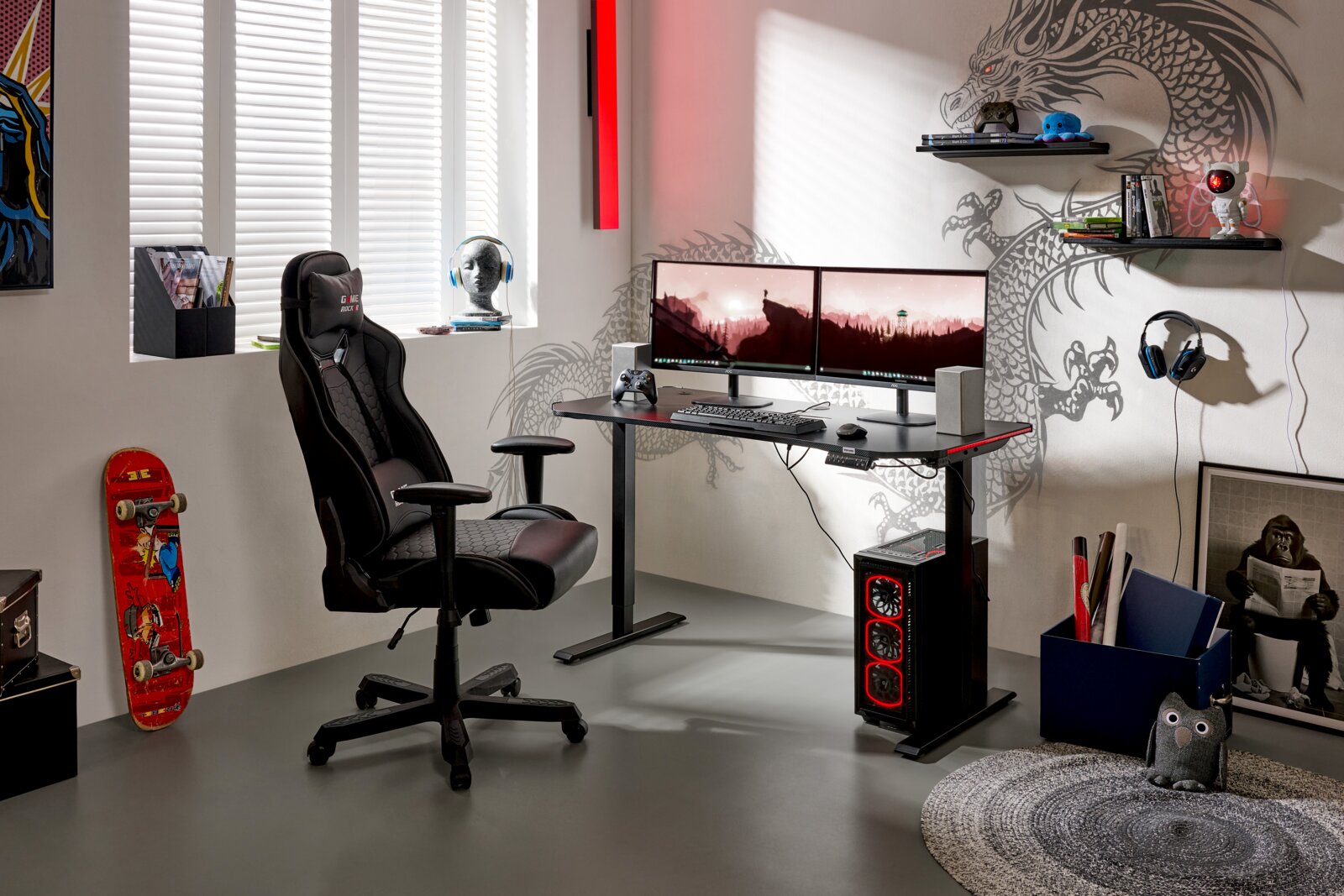 Modernes Gaming-Setup mit schwarzem Gaming-Stuhl, höhenverstellbarem Schreibtisch, zwei Monitoren und PC-Tower mit roter LED-Beleuchtung; Perspektive: frontale, leicht seitliche Gesamtansicht des Raums.