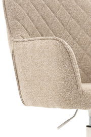 Nahaufnahme eines beigen Drehstuhls mit gepolstertem Stoffbezug und Armlehne, seitliche Perspektive