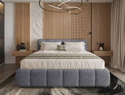 Frontale Ansicht eines modernen Polsterbettgestells mit grauem Stoffbezug, flankiert von Nachttischen und dekorativen Holzwänden im Hintergrund.