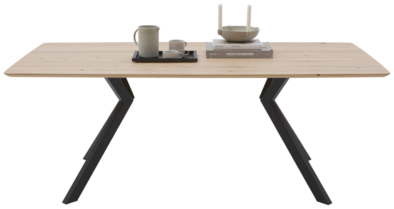 Moderner Esstisch mit Holzplatte und schwarzen Metallbeinen, frontal betrachtet, dekoriert mit Geschirr und Büchern.