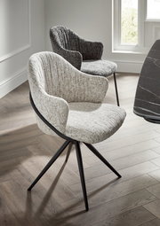 Zwei moderne Armlehnstühle mit Stoffbezug in hellen und dunklen Grautönen, auf einem Holzfußboden in einem hellen Raum, aus seitlicher Perspektive fotografiert.