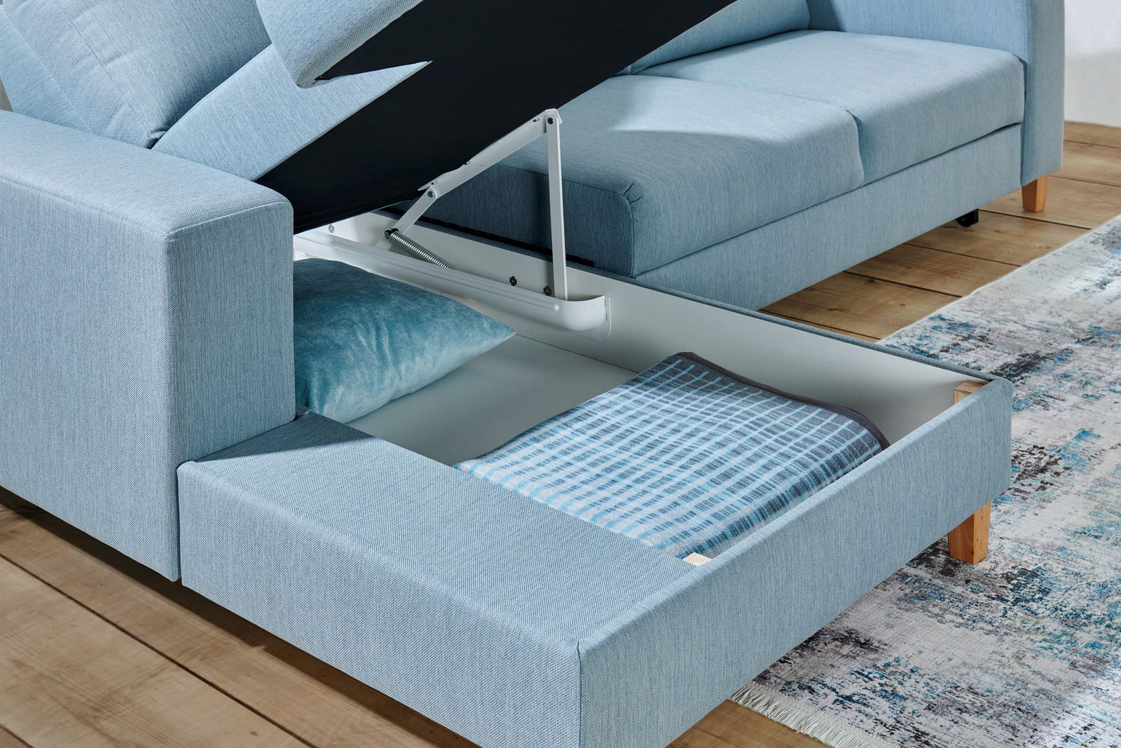 Rundecke Ottli in hellblauem Stoff mit geöffneter Stauraumfunktion, seitliche Perspektive