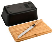 Schwarze Brotbox mit integriertem Messer, abgebildet aus der Vogelperspektive. Der Deckel der Box liegt umgedreht neben einem Holzbrett mit einem Brotmesser darauf.