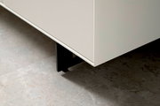 Nahaufnahme eines weißen Sideboards mit schwarzen Beinen, Perspektive von unten.