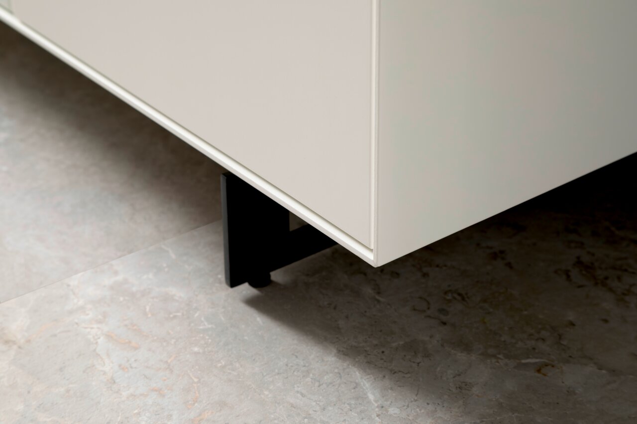 Nahaufnahme eines weißen Sideboards mit schwarzen Beinen, Perspektive von unten.