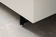 Nahaufnahme eines weißen Sideboards mit schwarzen Beinen, Perspektive von unten.