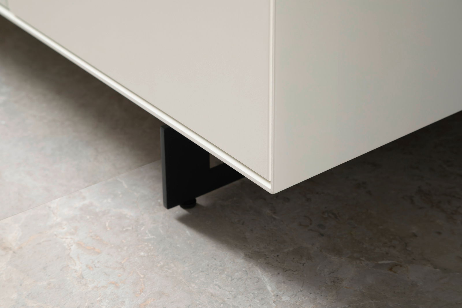 Nahaufnahme eines weißen Sideboards mit schwarzen Beinen, Perspektive von unten.