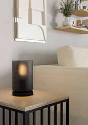 Moderne Tischleuchte COLOMERA in schwarzem, geripptem Design auf einem Holztisch, seitliche Perspektive.
