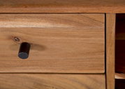 Nahaufnahme einer Holzschublade mit schwarzem Knopfgriff, perspektivisch von vorne.