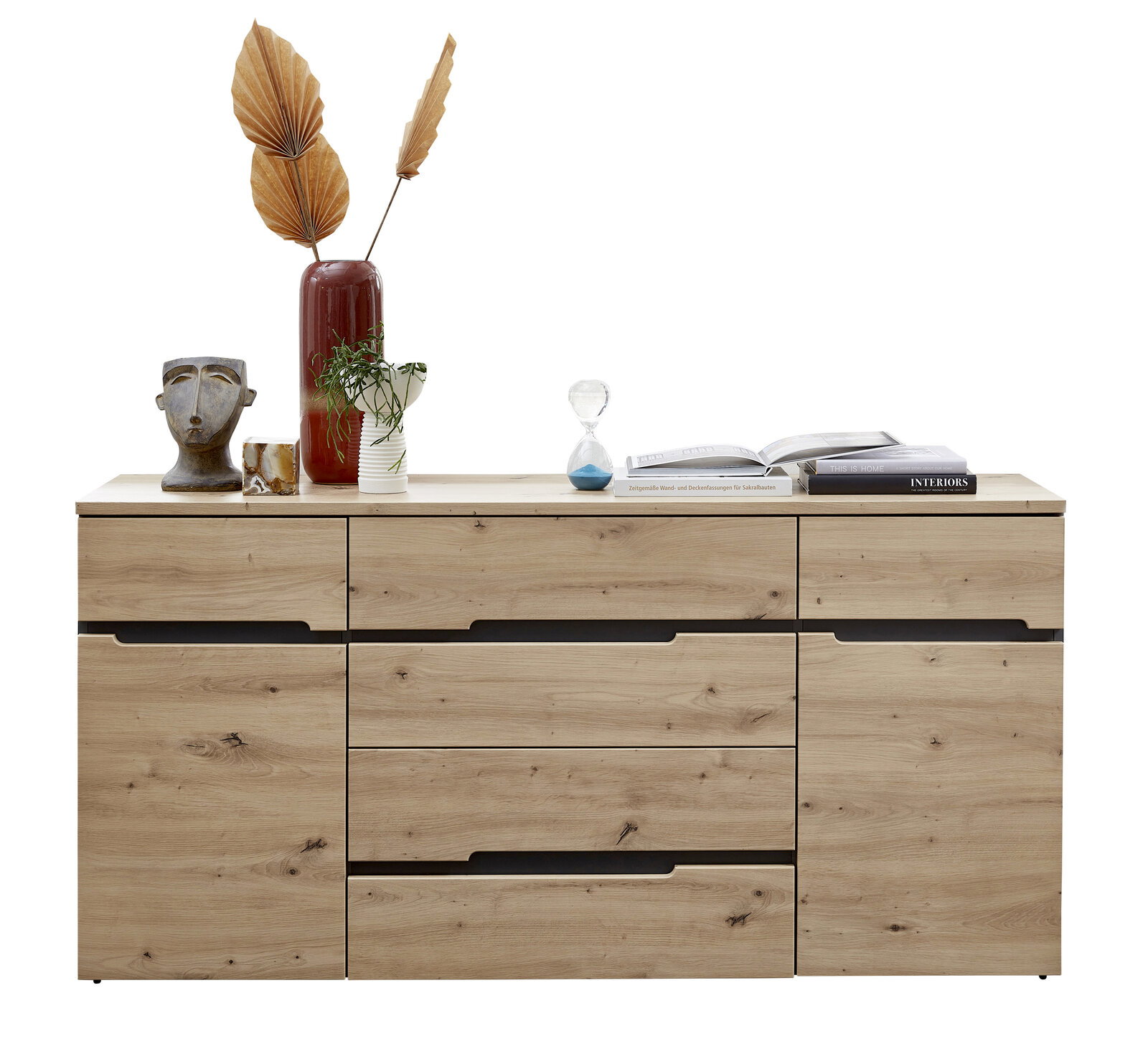 Frontale Ansicht eines modernen Sideboards aus Holz mit mehreren Schubladen und dekorativen Gegenständen darauf, darunter eine Vase mit getrockneten Blättern, eine Büste und Bücher.
