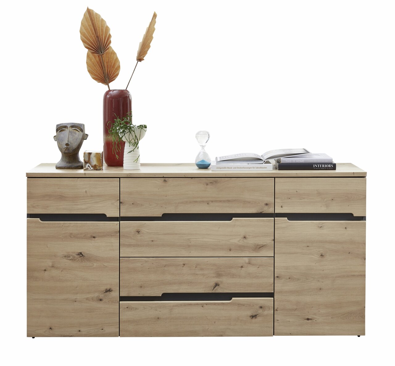 Z2 Sideboard MEMPHIS Frontale Ansicht eines modernen Sideboards aus Holz mit mehreren Schubladen und dekorativen Gegenständen darauf, darunter eine Vase mit getrockneten Blättern, eine Büste und Bücher.
