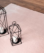 Rosa Teppich Loft Rose ca. 120x160cm auf Holzboden, mit zwei dekorativen schwarzen Laternen und weißen Kerzen, aus der Vogelperspektive.