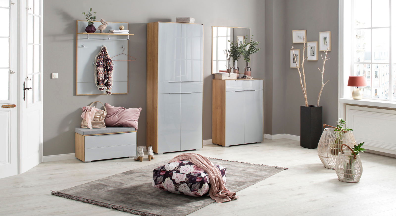 Moderne Garderobeneinrichtung mit Sitzkissen, Garderobenpaneel, Schuhschrank und Spiegel in einem hellen Raum mit großen Fenstern, aus der Perspektive des Betrachters von vorne gesehen.