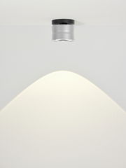 Moderne LED-Deckenleuchte MIKA in silberner Zylinderform, von unten betrachtet, mit sanftem Lichtkegel an der Decke.