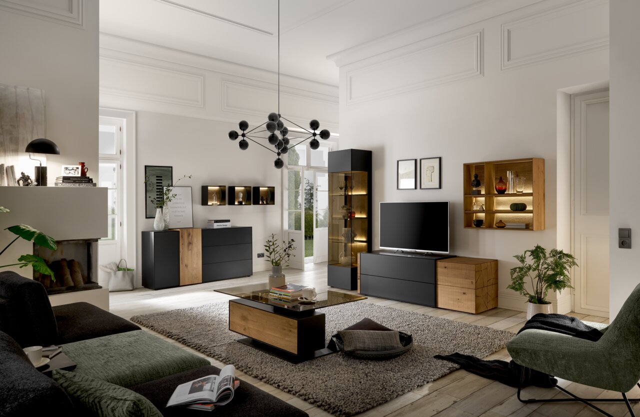 Musterring Wandkombination TREVIO Moderne Wohnzimmer-Wandkombination in einem stilvollen Raum mit schwarzem und holzfarbenem Design, inklusive TV-Schrank, Vitrine und Regalen. Perspektive: Frontalansicht.