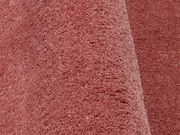 Nahaufnahme eines weichen, rosafarbenen Stoffes mit flauschiger Textur, perspektivisch von der Seite aufgenommen.