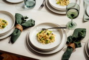Een elegante tafelsetting met wit servies, groene servetten en wijnglazen, gefotografeerd vanuit vogelperspectief.