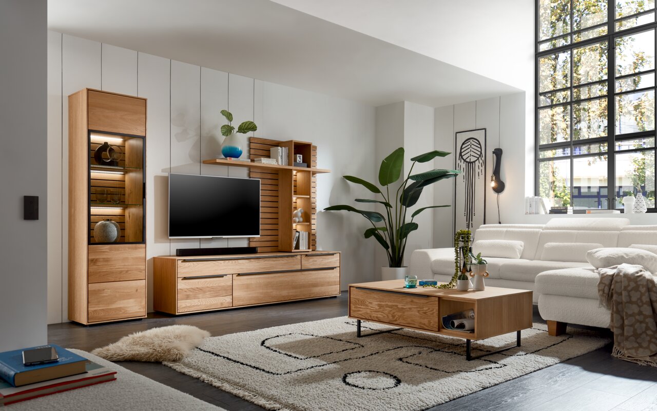 Set one by Musterring Couchtisch SET ONE JACKSON Moderne Wohnzimmermöbel in Holzoptik, bestehend aus einer Wohnwand mit TV, Vitrine und Couchtisch, aus der Perspektive eines gemütlichen Wohnzimmers mit großen Fenstern.