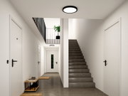 Moderne runde LED-Deckenleuchte mit schwarzem Rahmen in einem hellen Flur mit Treppe, Ansicht von unten nach oben (Untersicht)