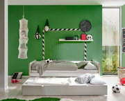 Jugendbett in einem Kinderzimmer mit grün gestrichener Wand, Fußball-Dekoration und einem ausziehbaren Bettkasten, seitliche Perspektive.
