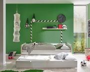 Jugendbett in einem Kinderzimmer mit grün gestrichener Wand, Fußball-Dekoration und einem ausziehbaren Bettkasten, seitliche Perspektive.