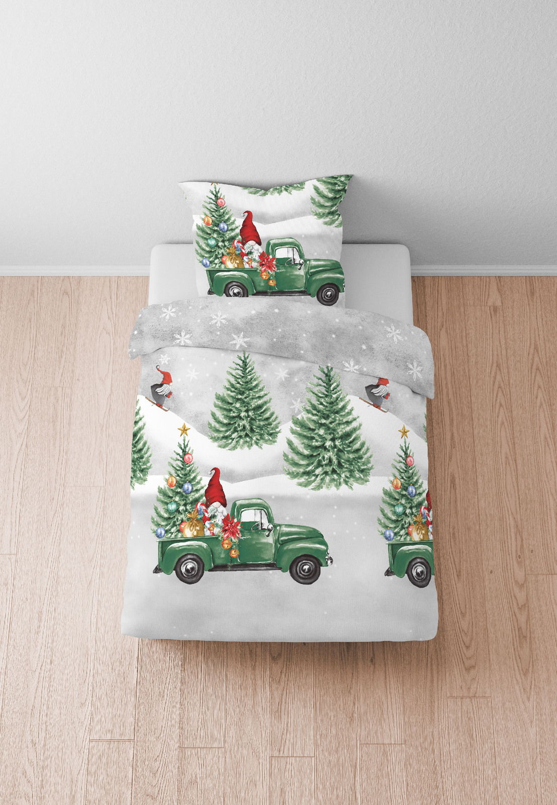 Bettwäsche-Set mit weihnachtlichem Motiv, bestehend aus einem grünen Truck, Weihnachtsbäumen und einem Weihnachtsmann, aus der Vogelperspektive fotografiert.