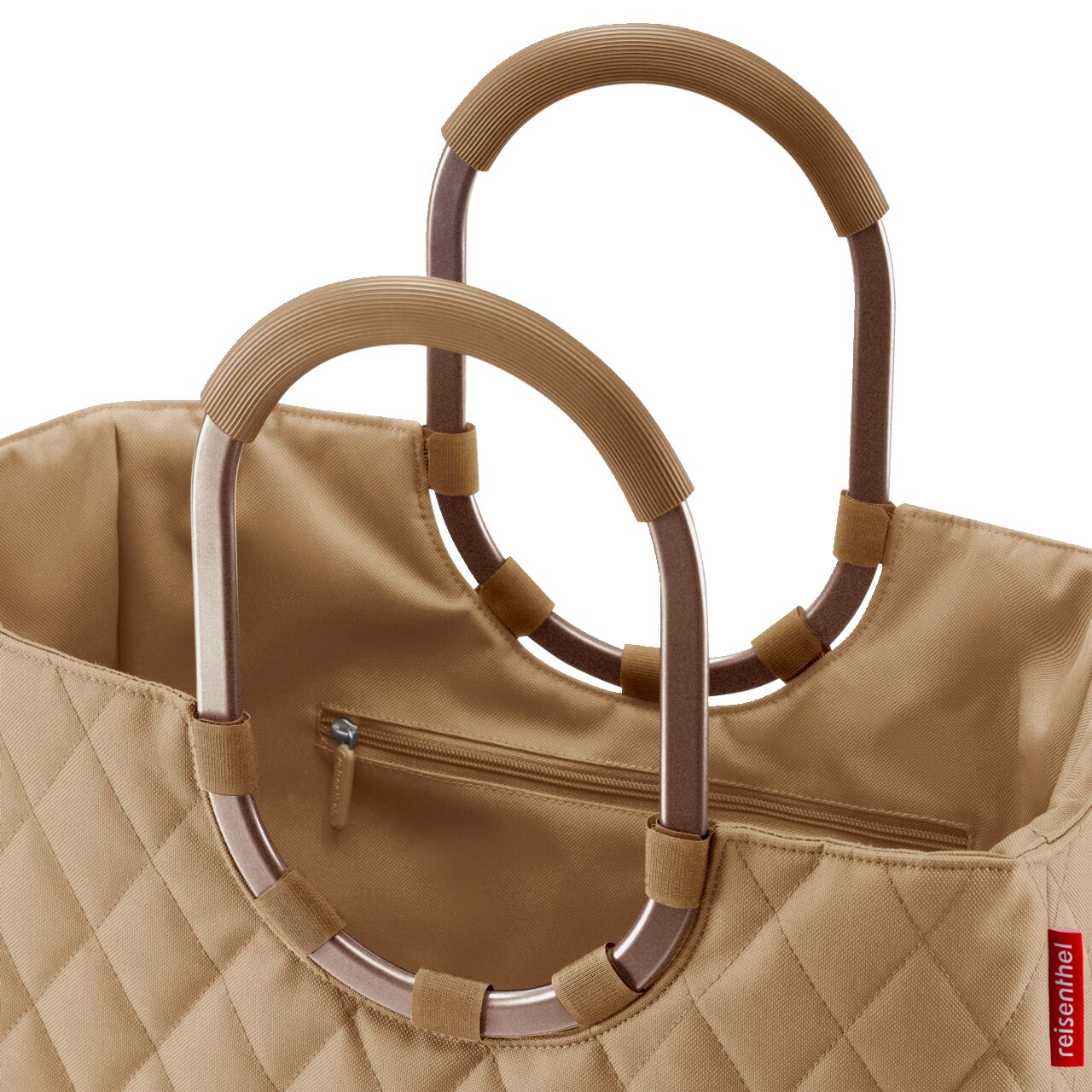 Nahaufnahme einer beigen, gesteppten Tasche mit ovalen Griffen aus Metall und Stoffüberzug, Perspektive von oben.