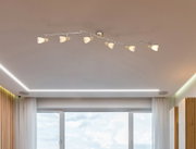 Deckenstrahler mit sechs verstellbaren Leuchten, montiert an einer modernen Wohnzimmerdecke, Perspektive von unten.