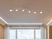 Deckenstrahler mit sechs verstellbaren Leuchten, montiert an einer modernen Wohnzimmerdecke, Perspektive von unten.