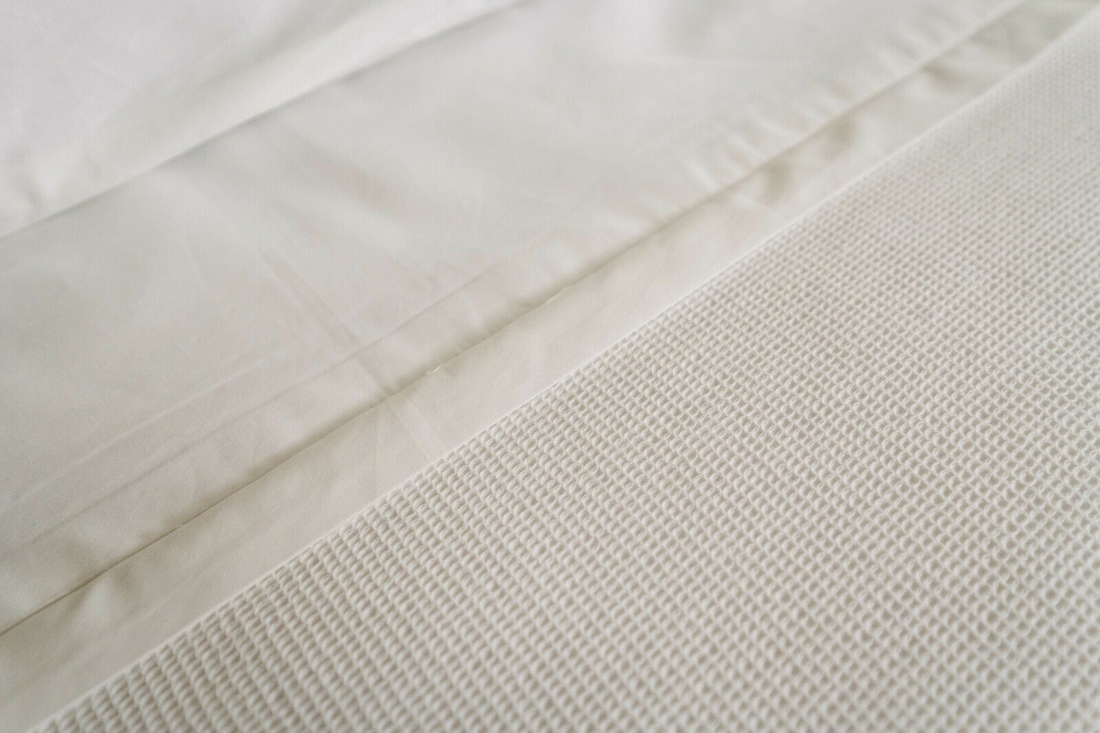 Nahaufnahme von weißer Bettwäsche mit strukturierter Oberfläche, von oben betrachtet