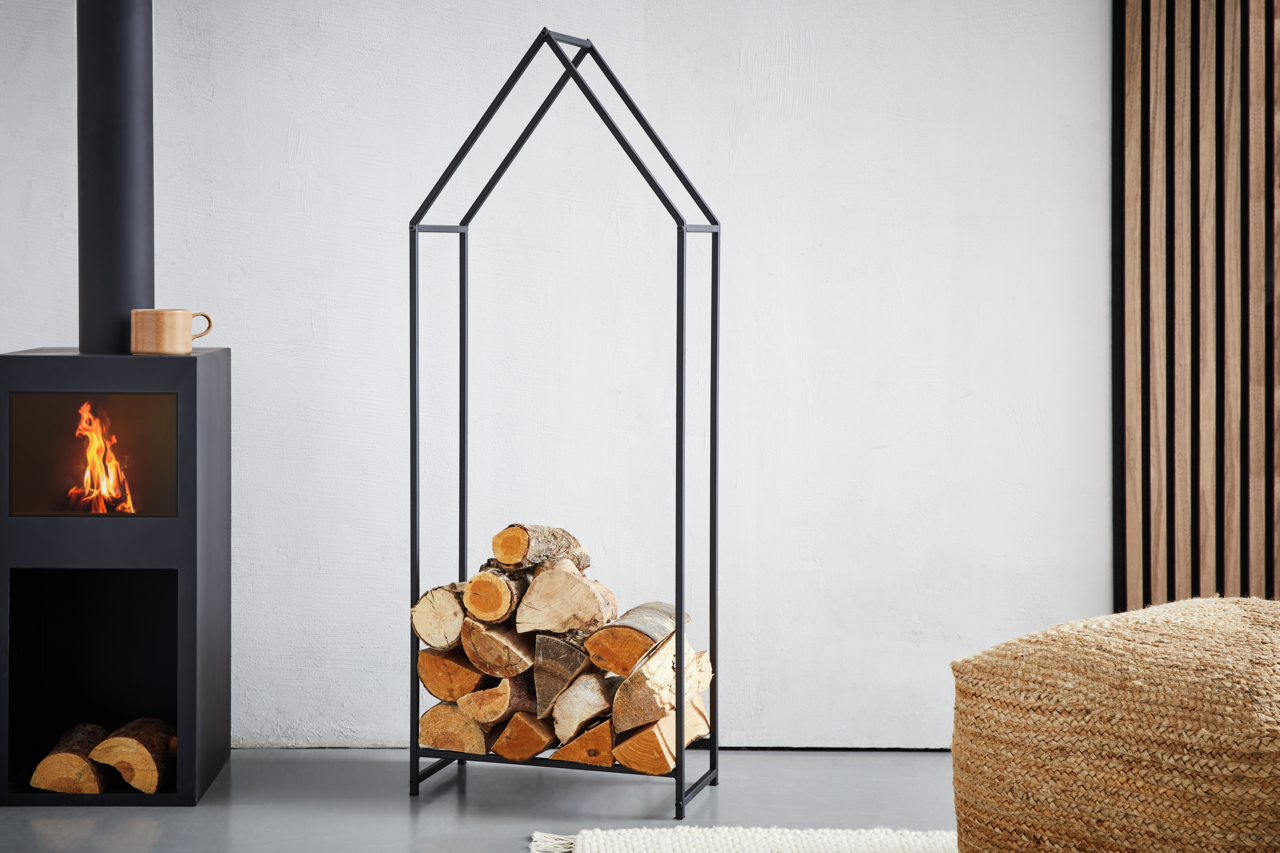 Moderner Kaminholzständer aus schwarzem Metall in Hausform, gefüllt mit Holzscheiten, seitliche Perspektive.