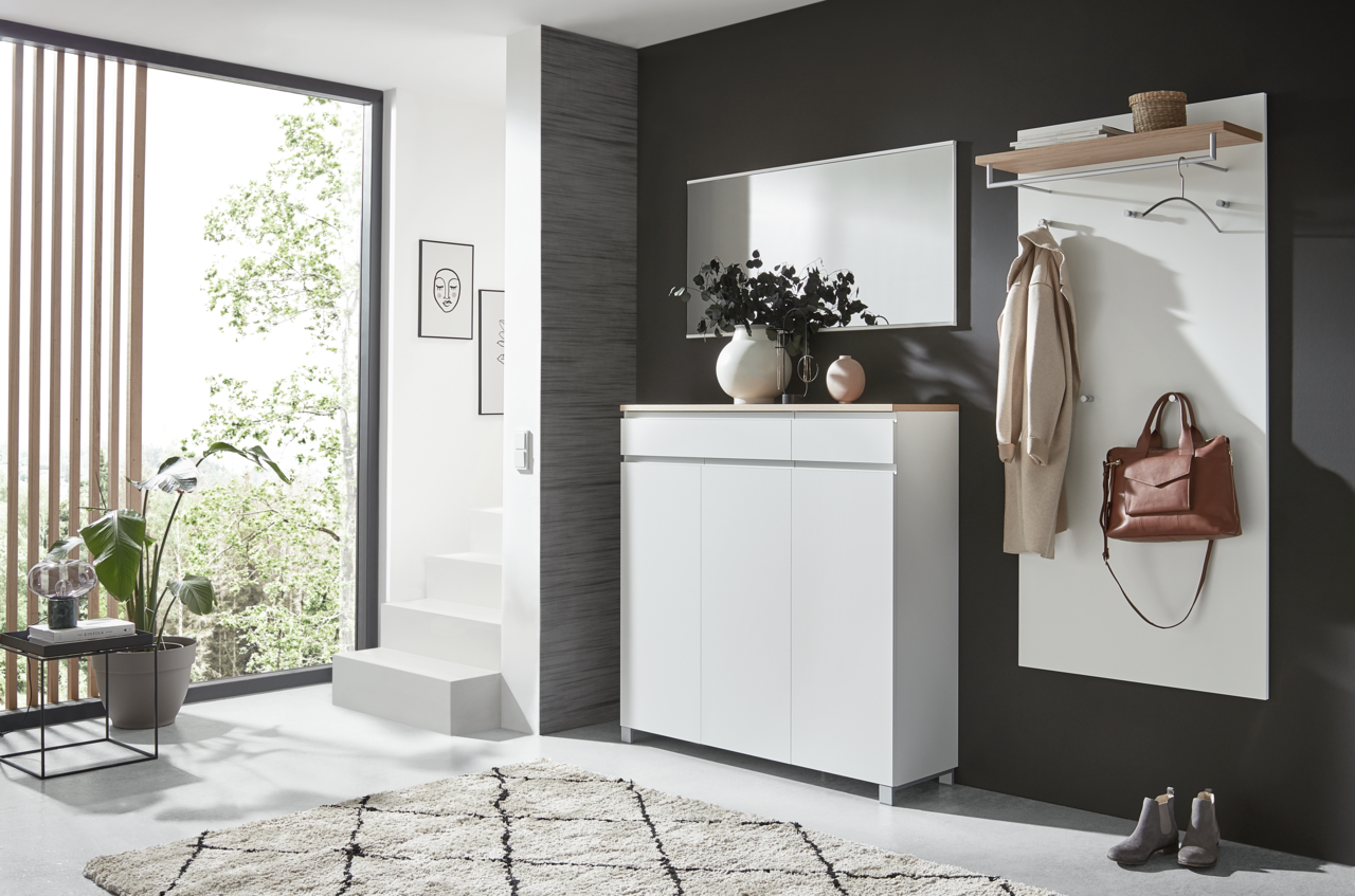 Moderner Eingangsbereich mit weißem Schuhschrank, Spiegel und Garderobenpaneel. Perspektive von der Seite.