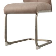 Nahaufnahme eines modernen Schwingstuhls mit beigem Polster und gebürstetem Metallgestell, seitliche Perspektive