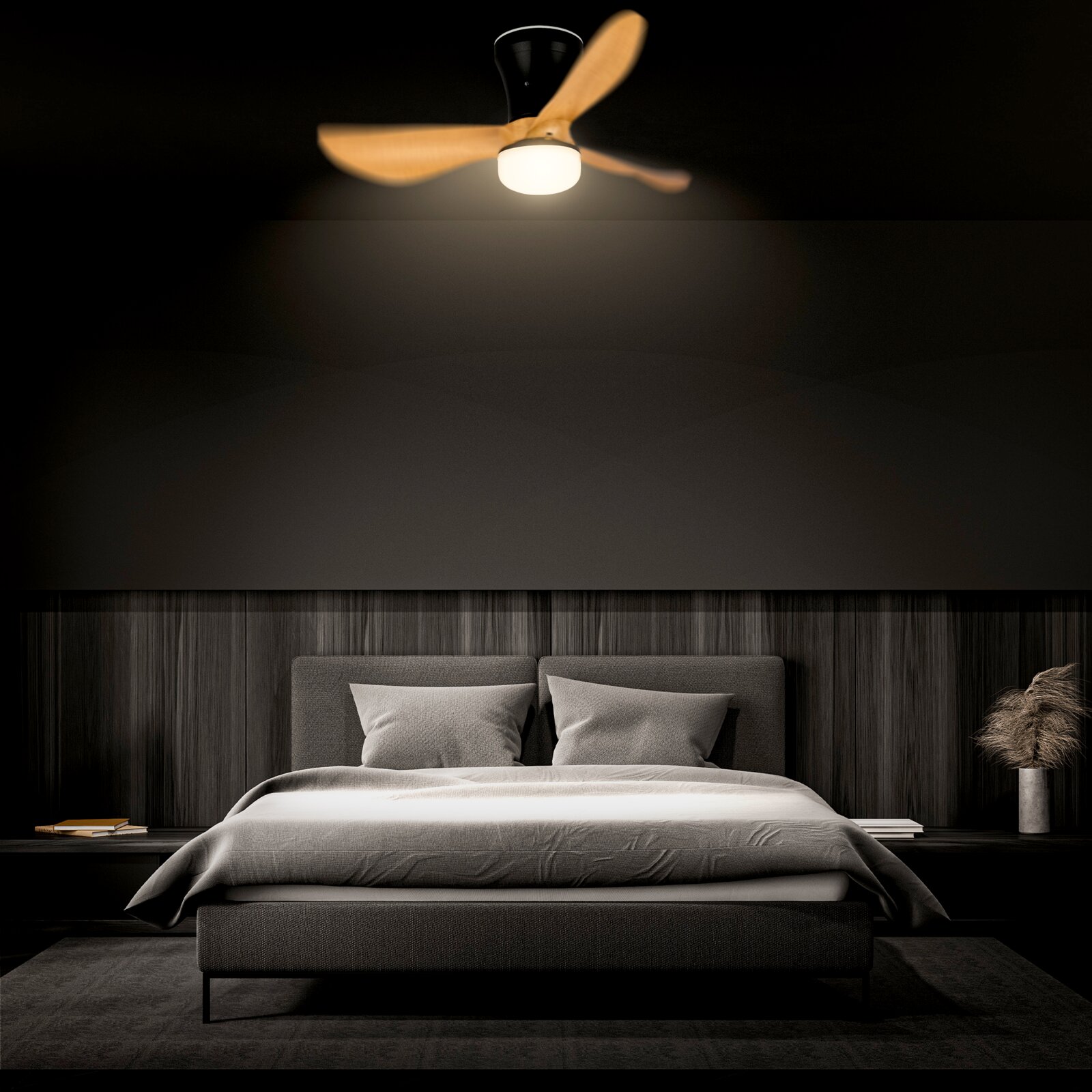 Moderner Deckenventilator mit integrierter LED-Leuchte, drei Holzflügeln und schwarzem Gehäuse über einem Bett im Schlafzimmer, Ansicht von unten in leichter Untersicht (Frontalperspektive)