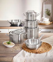 Topfset Gourmet Plus 6-tlg. aus Edelstahl, bestehend aus mehreren Töpfen und Pfannen mit Deckeln, auf einer Küchenarbeitsplatte von vorne fotografiert.