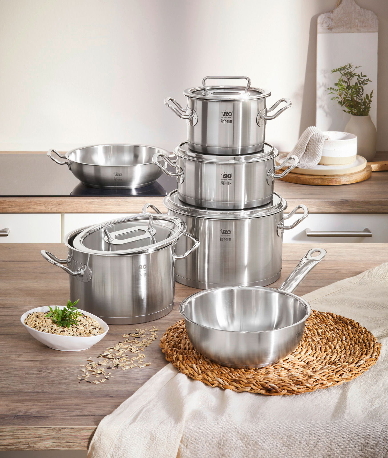 Topfset Gourmet Plus 6-tlg. aus Edelstahl, bestehend aus mehreren Töpfen und Pfannen mit Deckeln, auf einer Küchenarbeitsplatte von vorne fotografiert.