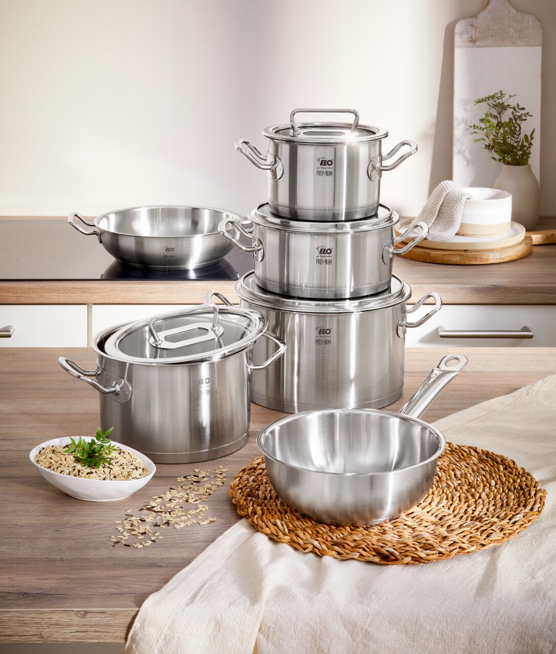 Topfset Gourmet Plus 6-tlg. aus Edelstahl, bestehend aus mehreren Töpfen und Pfannen mit Deckeln, auf einer Küchenarbeitsplatte von vorne fotografiert.