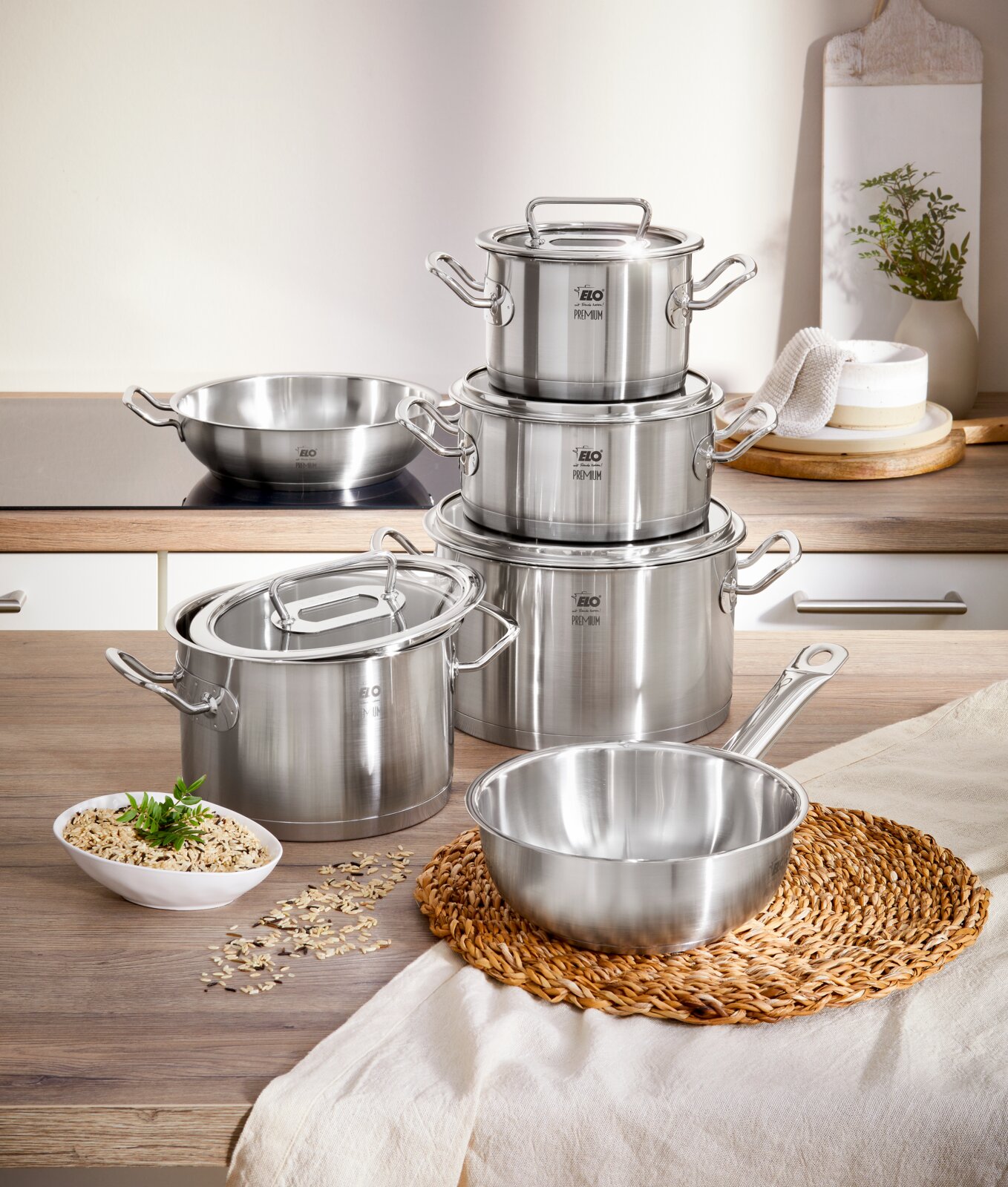 Topfset Gourmet Plus 6-tlg. aus Edelstahl, bestehend aus mehreren Töpfen und Pfannen mit Deckeln, auf einer Küchenarbeitsplatte von vorne fotografiert.