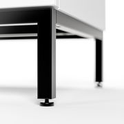 Nahaufnahme eines schwarzen Metallgestells mit verstellbaren Füßen, perspektivisch von unten links betrachtet.