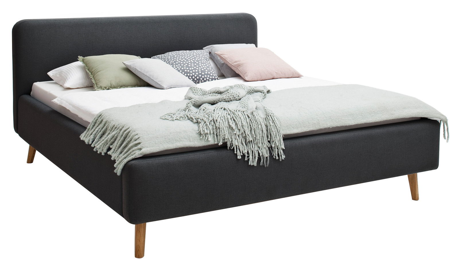 Polsterbett in Dunkelgrau mit Holzfüßen, dekoriert mit mehreren Kissen und einer Decke, seitliche Perspektive