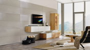Moderne Wohnwand ohne Beleuchtung in einem hellen Wohnzimmer mit großen Fenstern, bestehend aus hängenden und stehenden Elementen in Holz- und Weißtönen, seitliche Perspektive.
