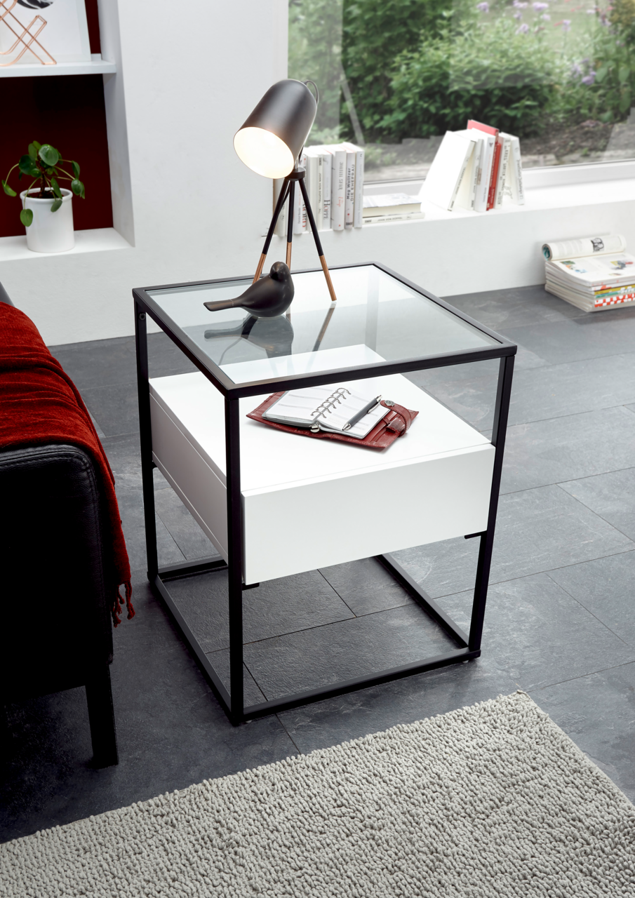 Zurbrüggen Beistelltisch EVORA Moderner Beistelltisch mit Glasplatte und schwarzem Metallrahmen, von oben fotografiert. Auf dem Tisch stehen eine Lampe und ein Notizbuch.