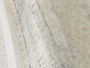 Nahaufnahme eines Designer-Teppichs mit floralen Mustern in Beige- und Grautönen, seitliche Perspektive.