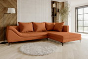 Modernes orangefarbenes Ecksofa mit Recamiere rechts, vier Rückenkissen und schwarzen Metallfüßen in hellem Wohnzimmer, Frontansicht leicht schräg von links