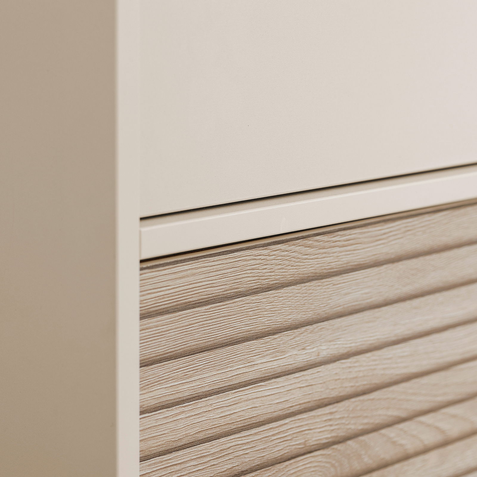 Nahaufnahme eines Paidi Kleiderschranks EEFJE mit einer Kombination aus glatter und holzstrukturierter Oberfläche.