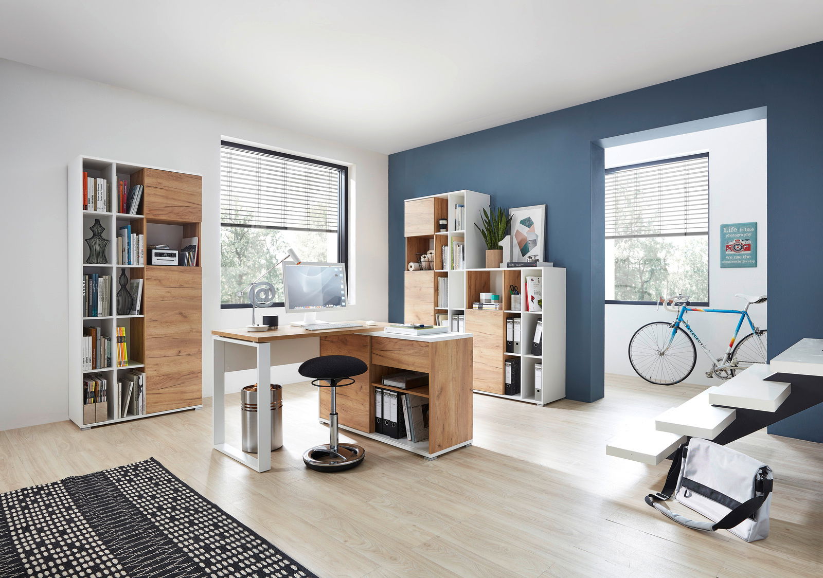 Moderner Büroraum mit Schreibtisch, Rollcontainer und Aktenschränken in Holzoptik, seitliche Perspektive